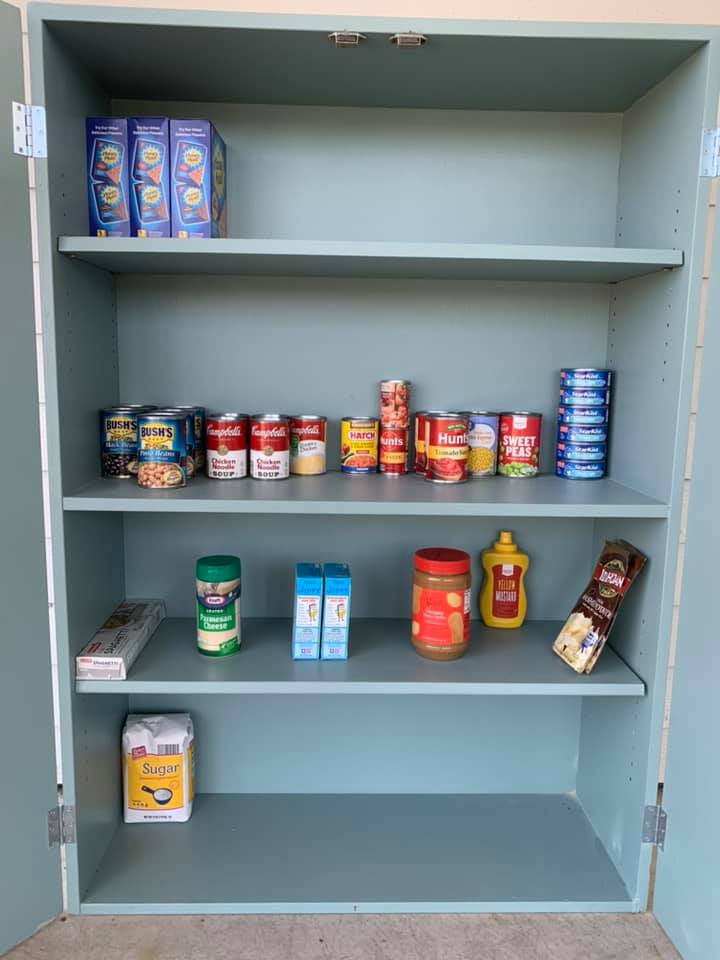 Inside the pantry cabinet showing canned goods and staple foods